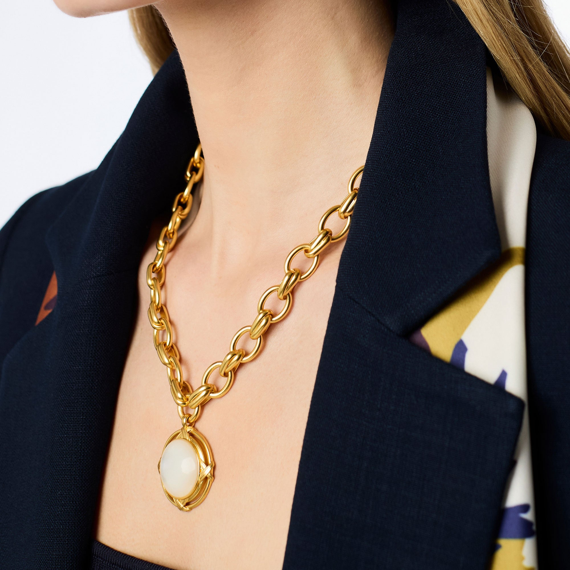 Close-up of a woman wearing the gold Essex Statement Necklace with a large white stone pendant.