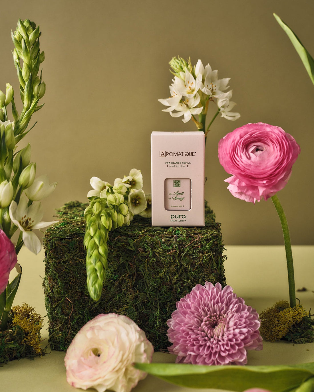 The Smell of Spring Pura Refill box on a mossy block surrounded by fresh spring flowers.