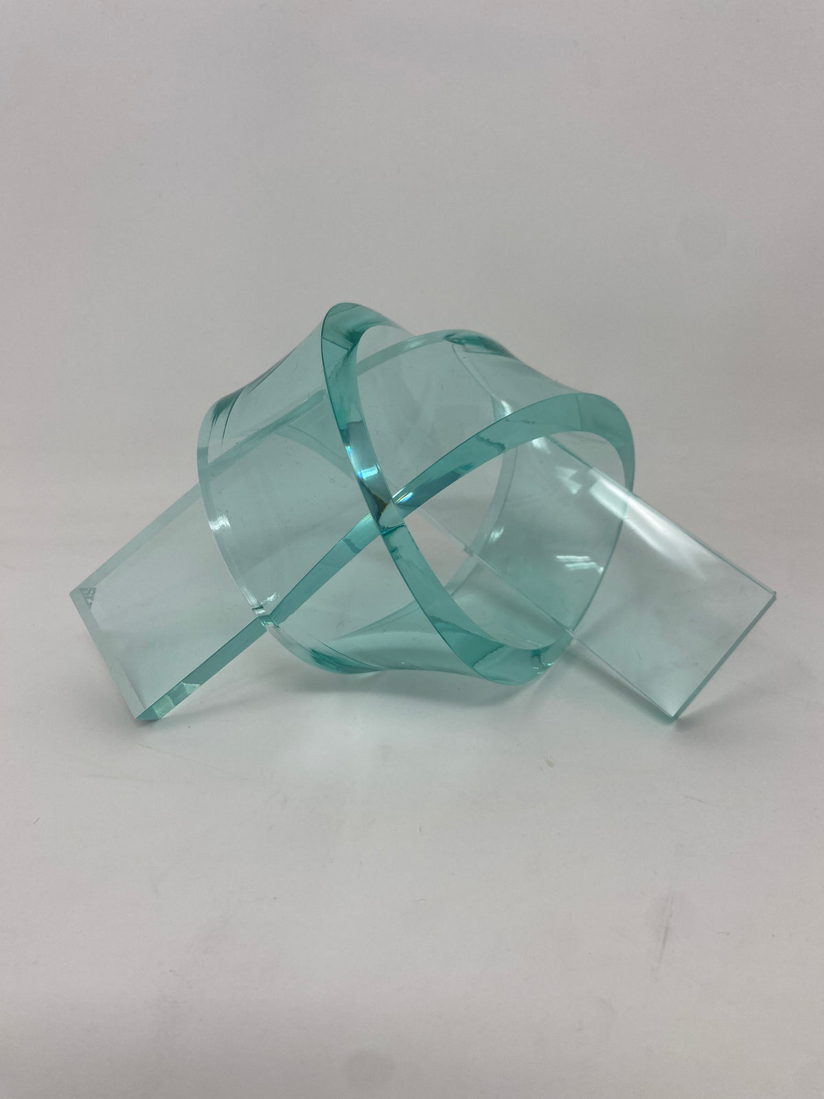 Acrylic knot pendant with a smooth geometric shape in clear material.