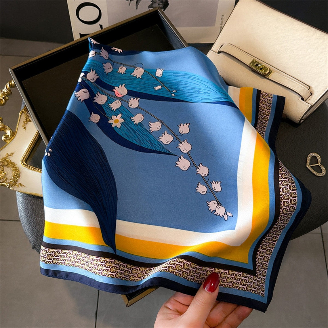 Blue artistic printed small square scarf with lily of the valley floral design and yellow border.