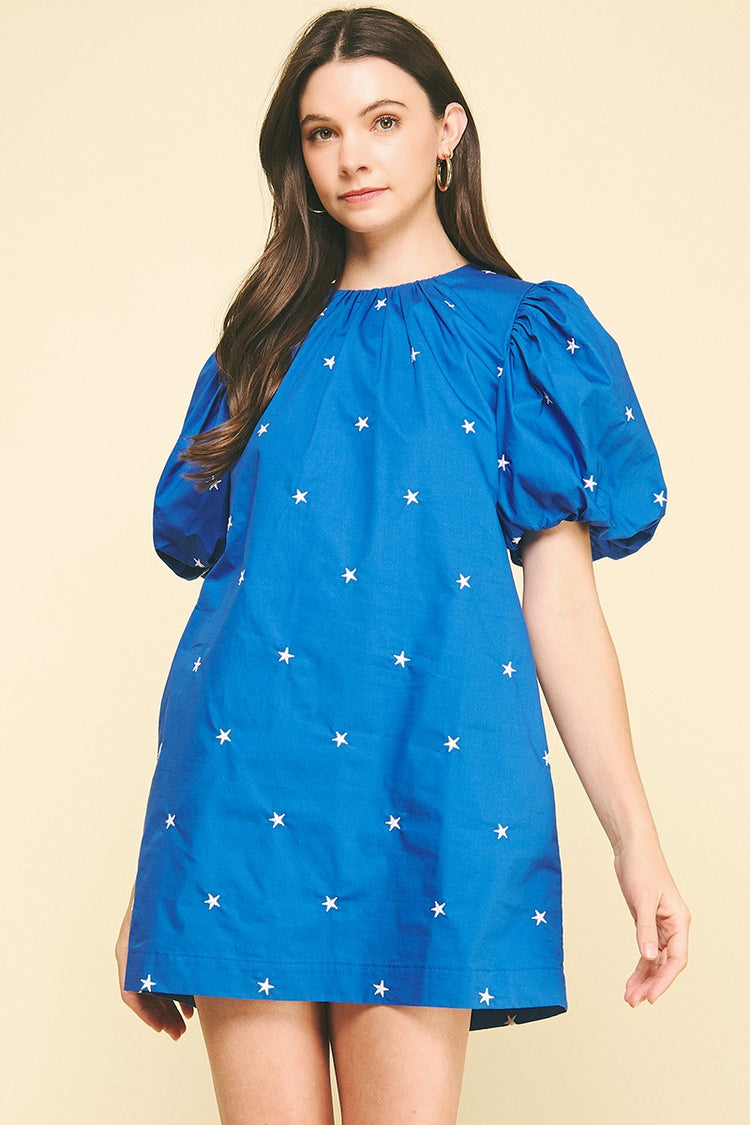 A woman wearing the Miggy Star Embroidered Mini Dress in royal blue with white star patterns.
