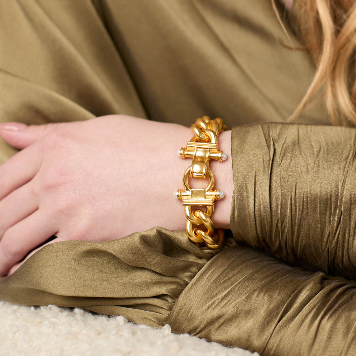 Close-up of a person wearing a gold-plated Dolce Link Bracelet with glass pearl accents.