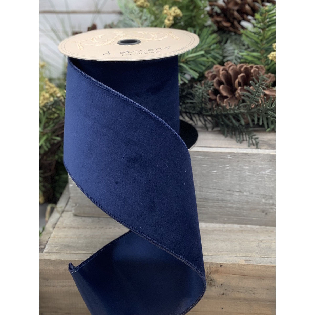 A roll of dark blue velvet ribbon with a taffeta backing, 2.5 inches wide.