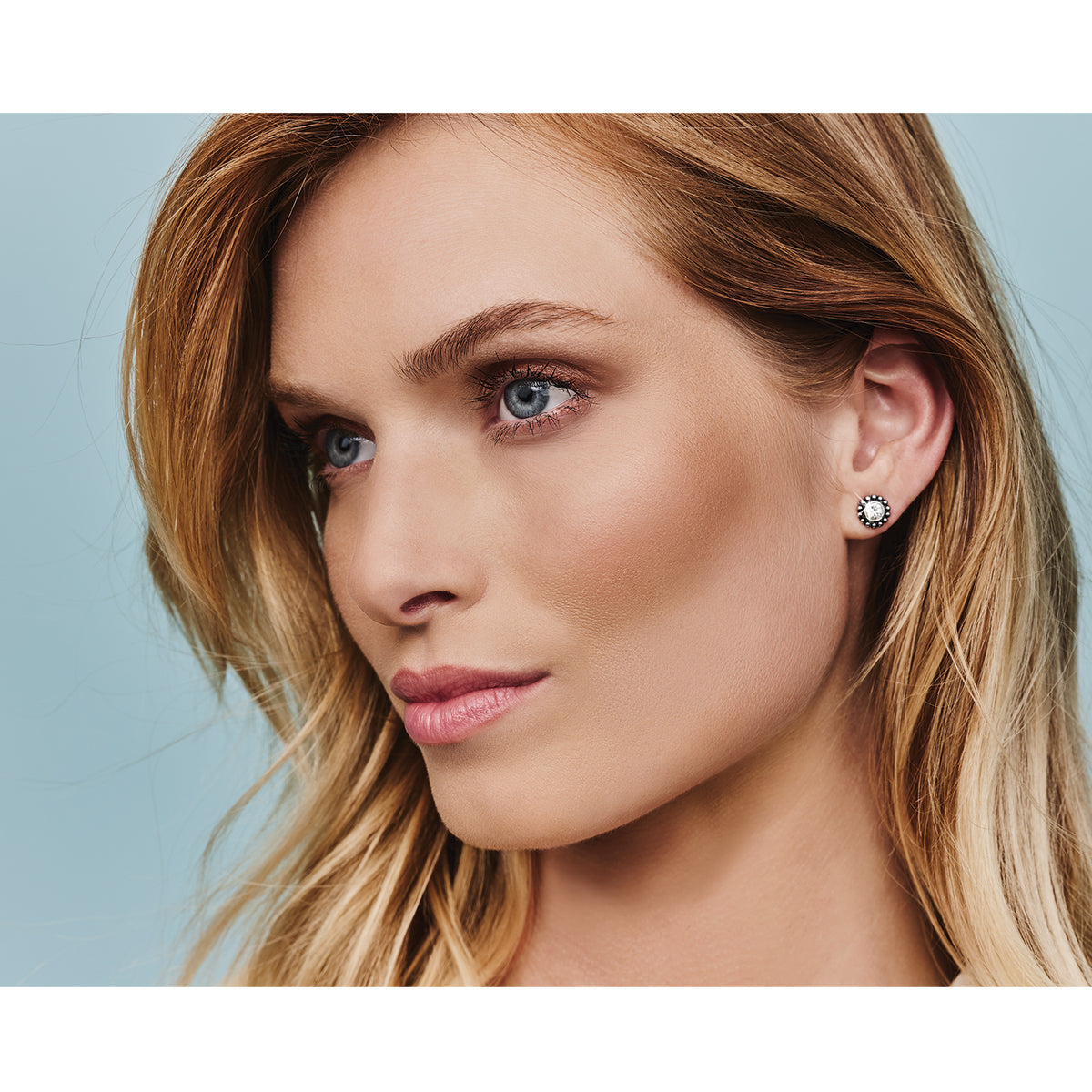A woman wearing the Twinkle Mini Post Earrings in silver, featuring a round crystal design.