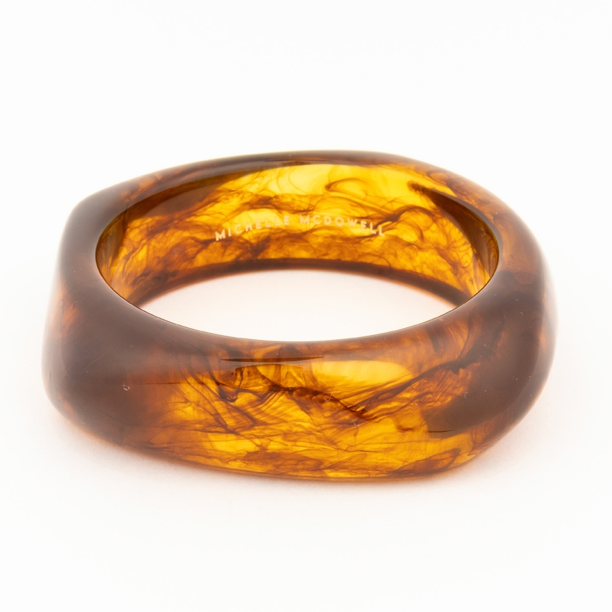 Tillie Bangle in tortoiseshell resin with a thick, organic shape and Michelle McDowell branding.
