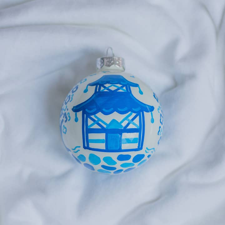 Hand-painted ceramic ornament featuring a pagoda scene with red roof tiles against a white background.
