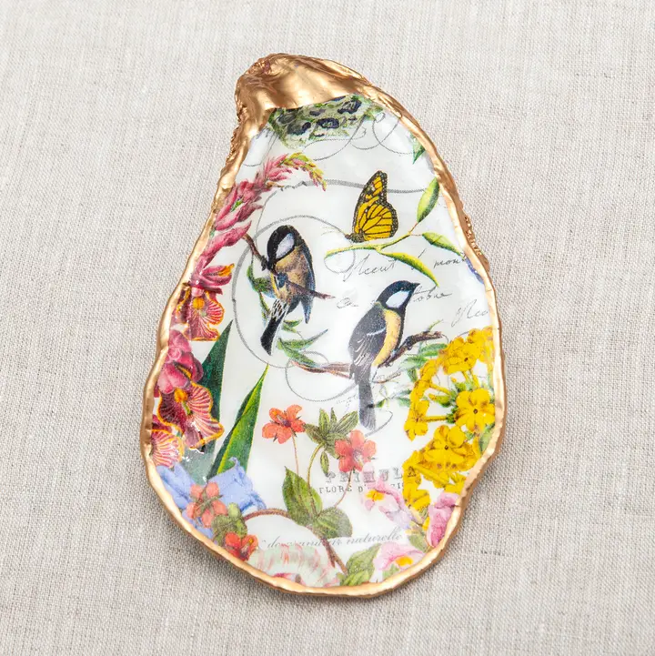 Decoupaged oyster shell with birds, butterfly, and flowers, finished with a metallic gold rim.