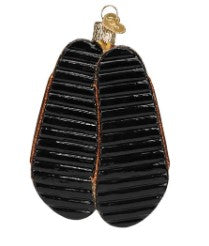 Bottom view of a black sandals Christmas ornament with textured soles and a gold hanging loop.