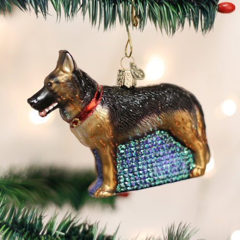 German Shepherd dog ornament in black resin with white accents on a gold stand.