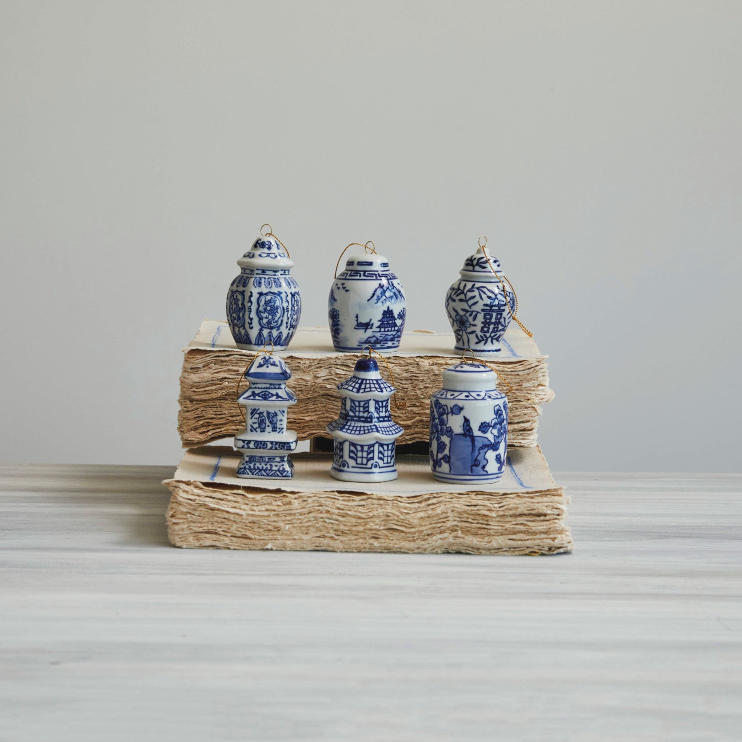 Set of six miniature blue and white stoneware ginger jar and pagoda ornaments on stacked paper.