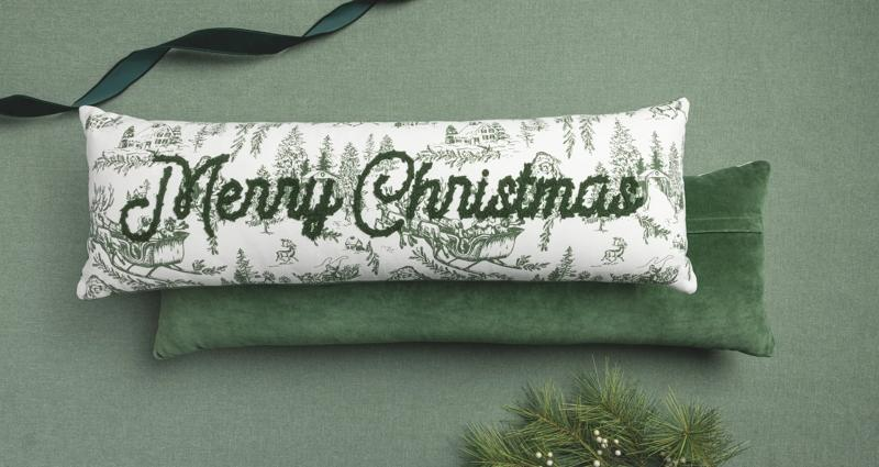 Merry Christmas Toile Long Pillow with green script embroidery and a winter scene pattern.