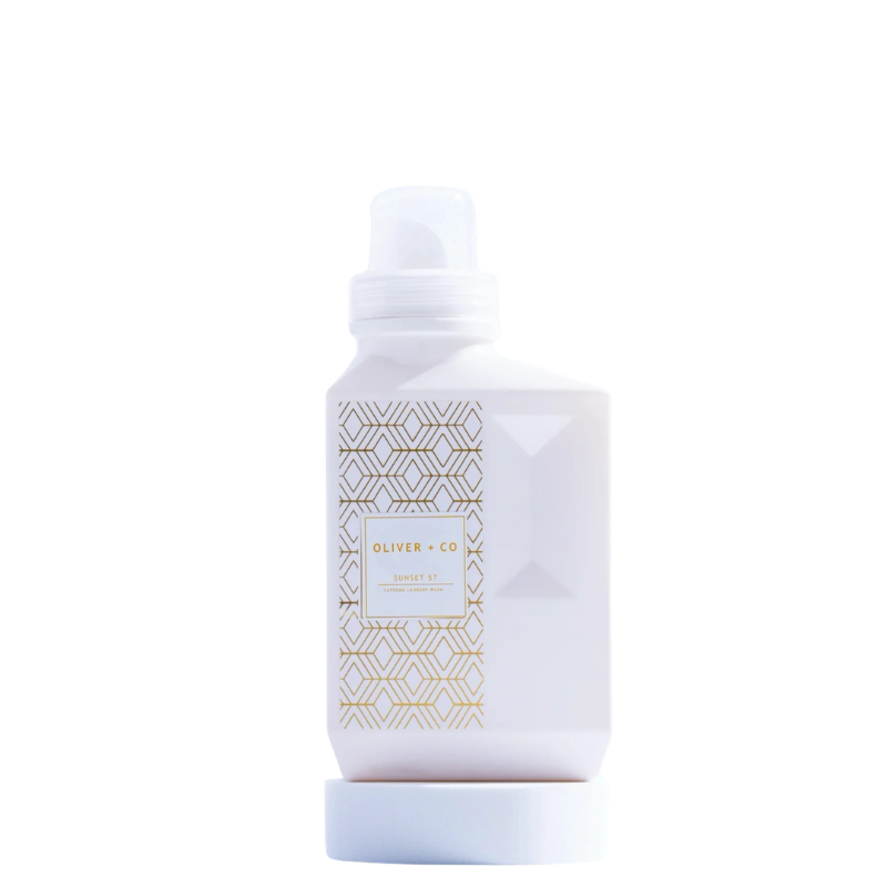 Oliver + Co Supreme Laundry Wash in a white bottle with a gold geometric pattern.