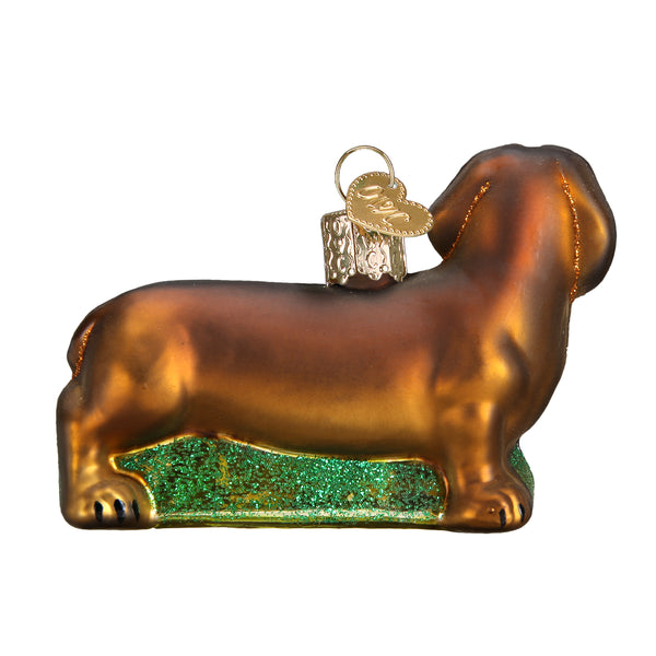 Brown glass Dachshund Christmas ornament with a gold heart charm and green glitter base.