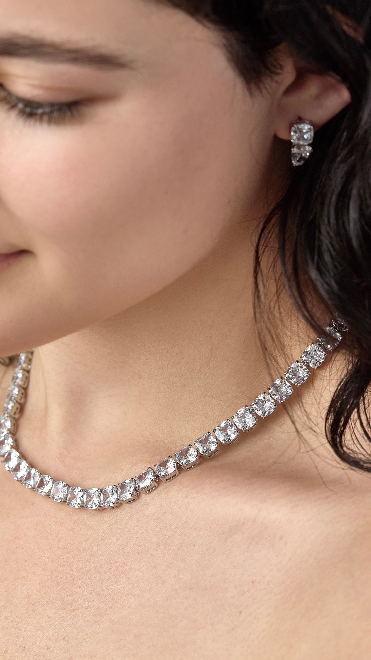 Close-up of a woman wearing a Clair Tennis Necklace with square-cut cubic zirconia stones.