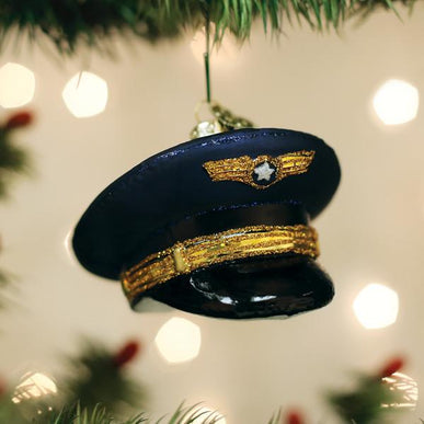 Blue glass pilot's cap Christmas ornament with gold glitter accents hanging on a tree.