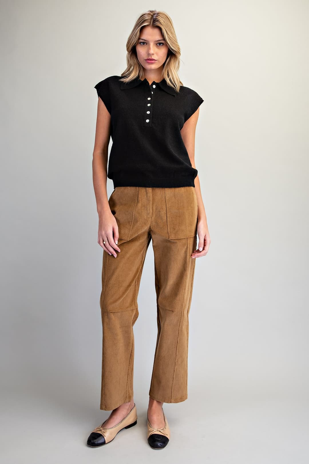 Woman wearing a black Lily Polo Collar Cap Sleeve Knit Top with tan corduroy pants.