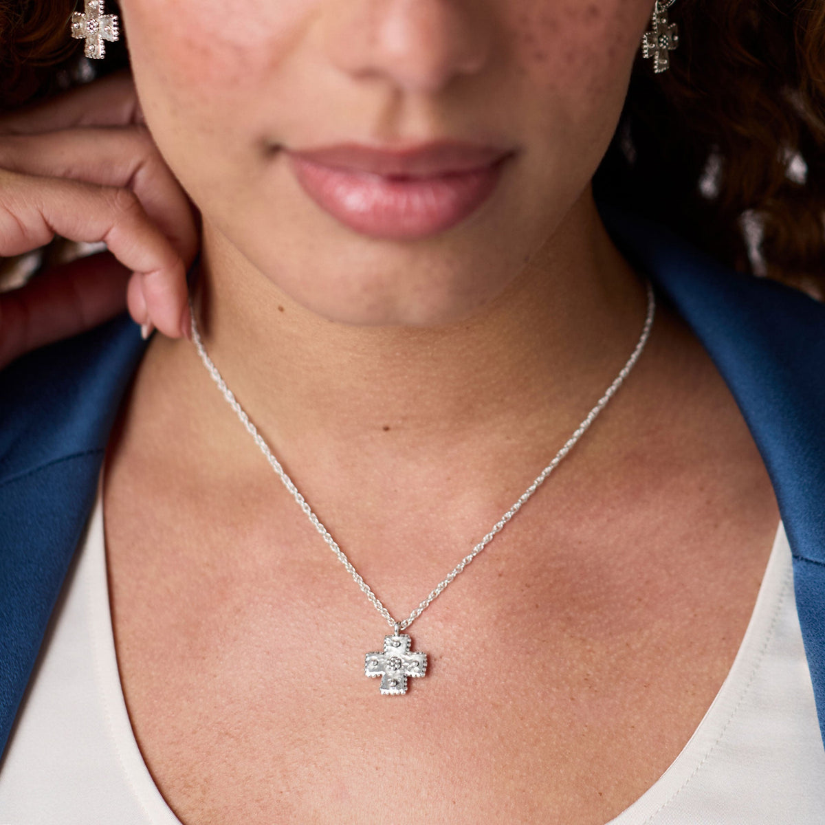 Woman wearing the silver Canterbury Delicate Necklace featuring a hand-hammered cross pendant.