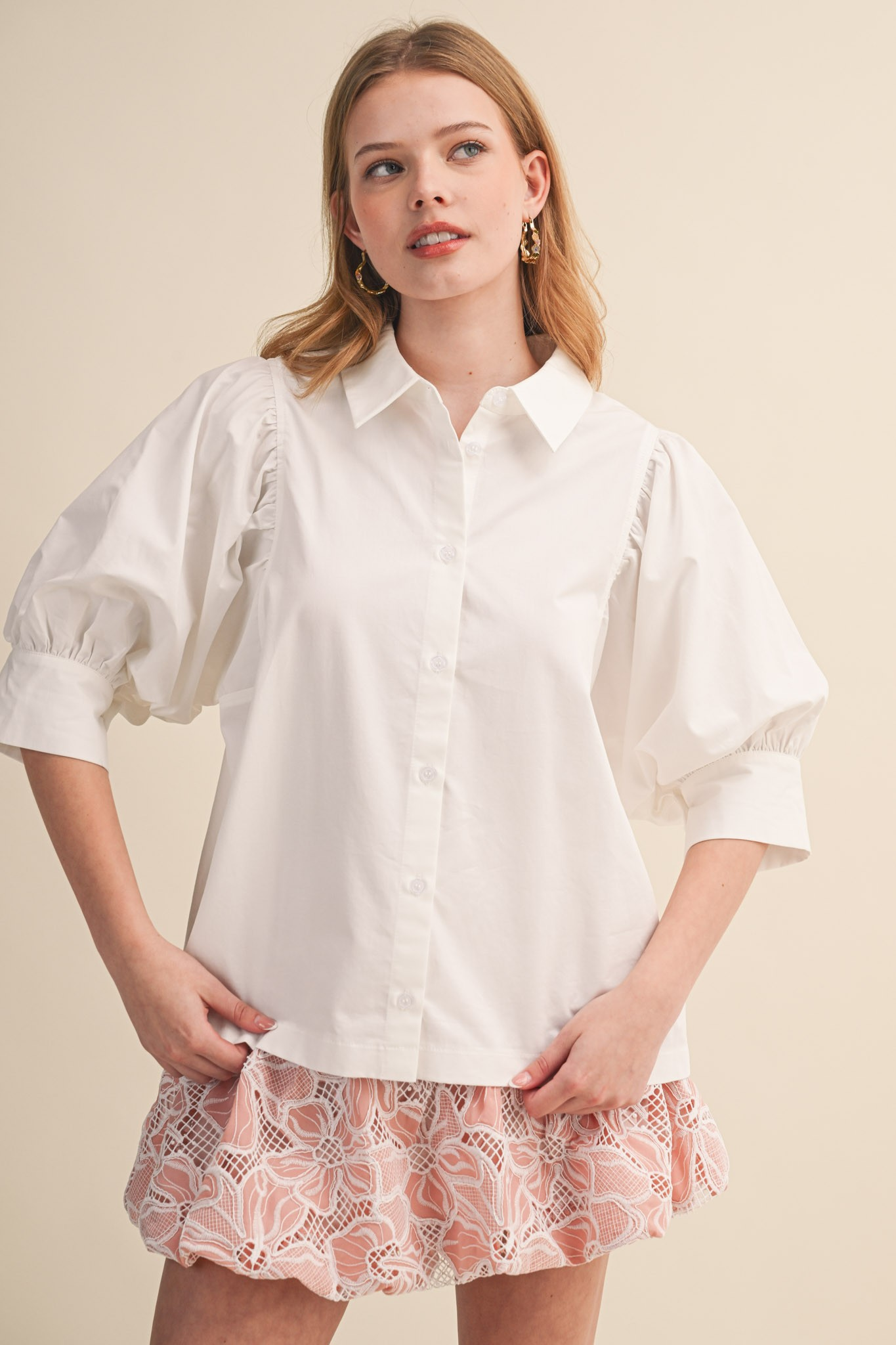Woman wearing a white Krisha Puff Sleeve Button Down Top with a pink lace skirt.