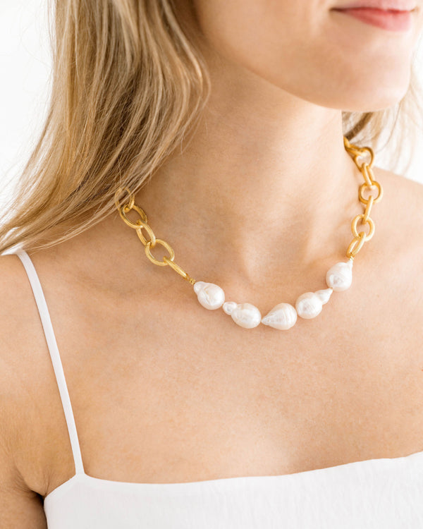 Woman wearing a Baroque Pearl Chain Necklace with gold links and white irregular pearls.