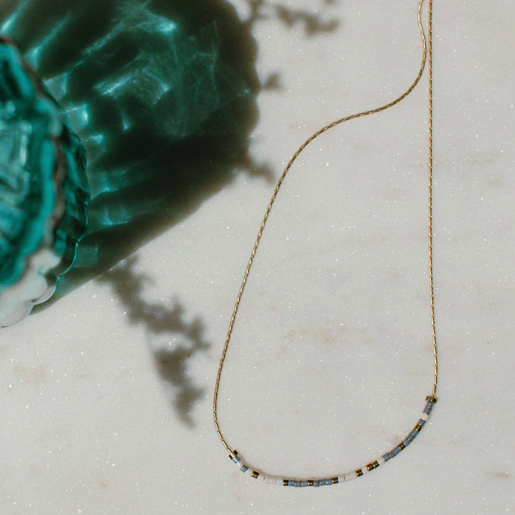 Choose Joy Morse code necklace with pearl white and gray beads on a gold chain.