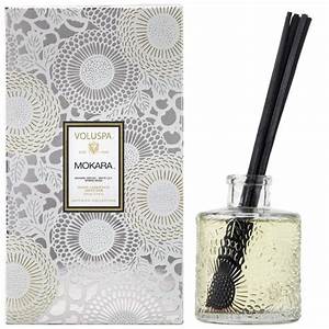 Reed diffuser bottle with clear glass body containing amber liquid and floating reeds.