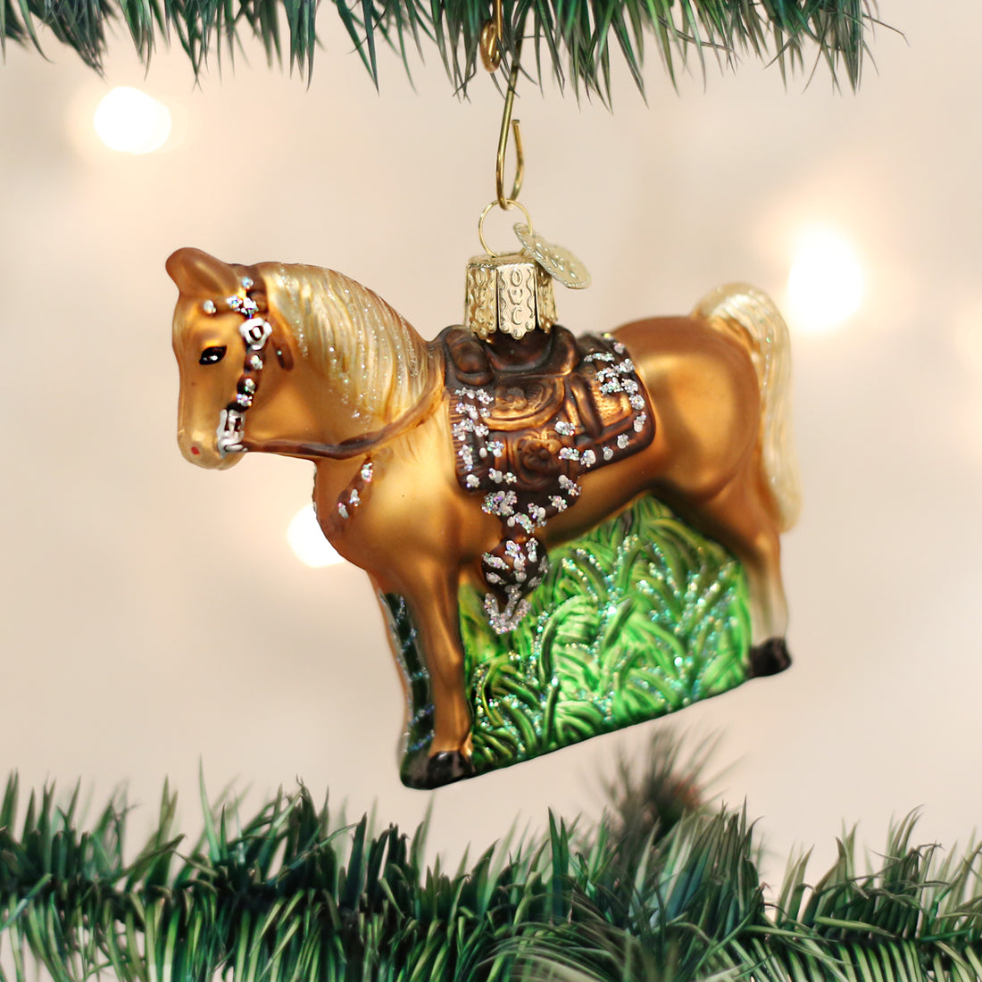 Glass Western Horse Ornament with a brown saddle and glitter accents hanging on a Christmas tree.