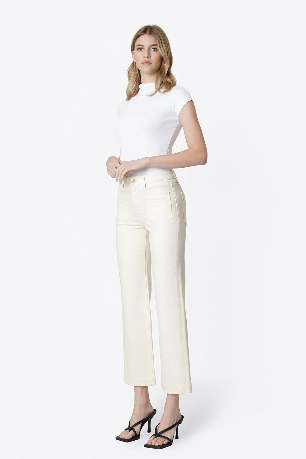 Model wearing Ailleah High Rise Slim Wide Leg jeans in natural color with a white mock neck top.