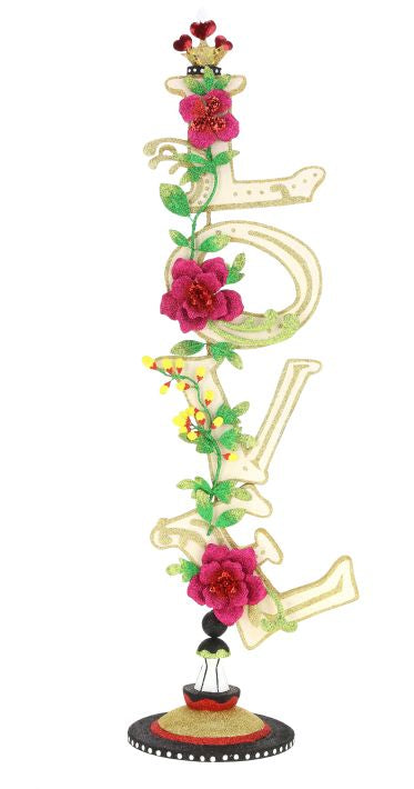 A tall, glittery gold "LOVE" finial with pink flowers and green vines, topped with a crown.