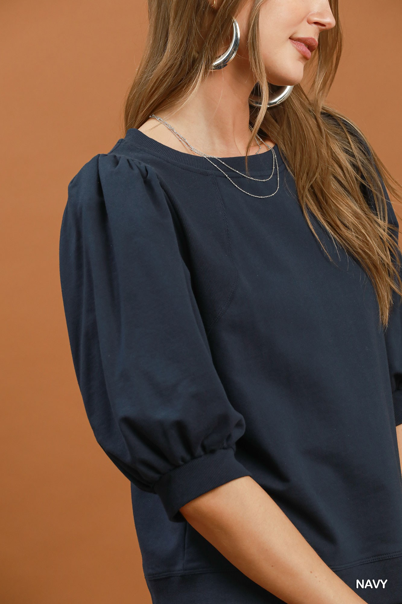 Close-up of a woman wearing a navy blue Joyce Puff Sleeve Pullover Sweatshirt Top.