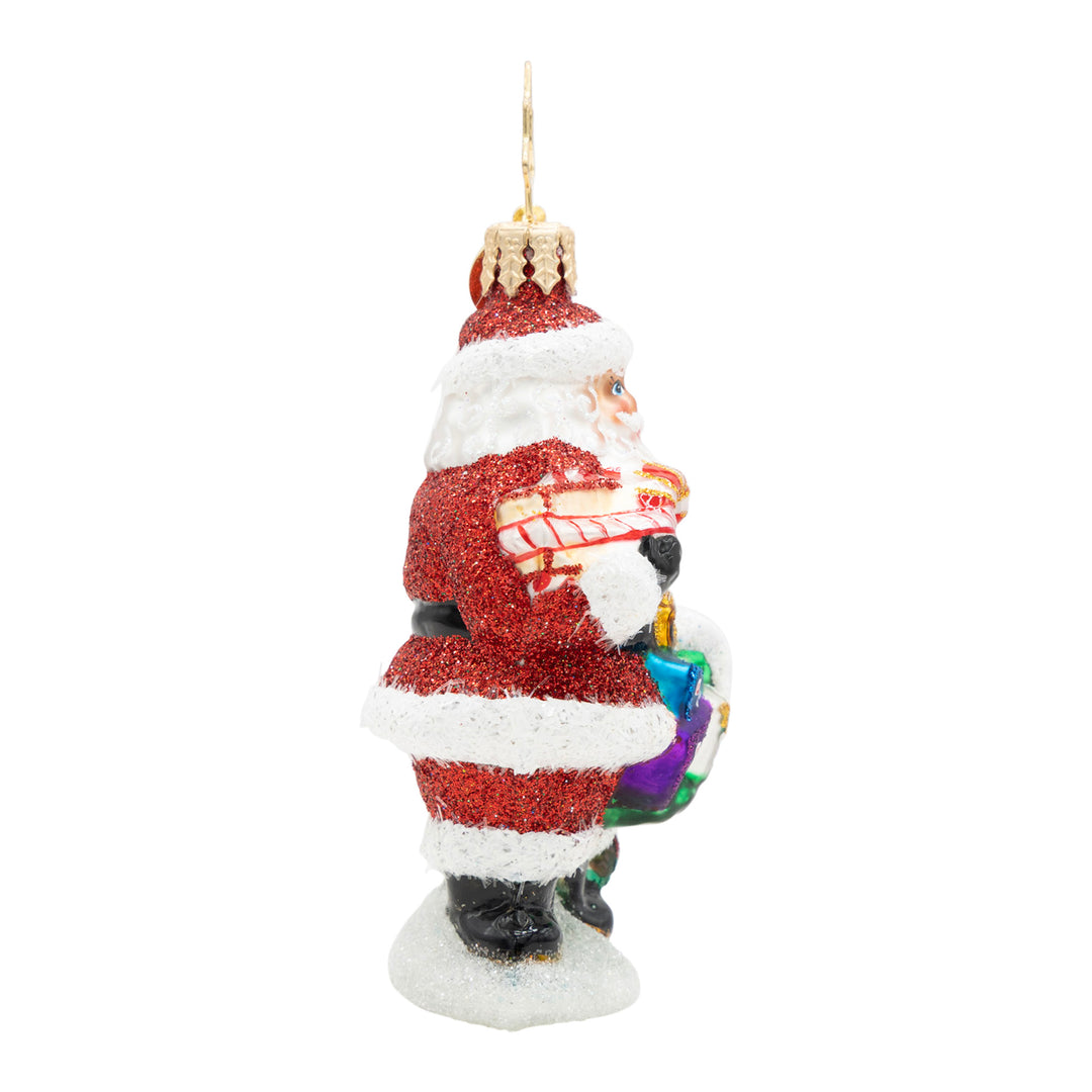 Side view of a glittery Santa Claus glass ornament holding a mailbox and gifts.