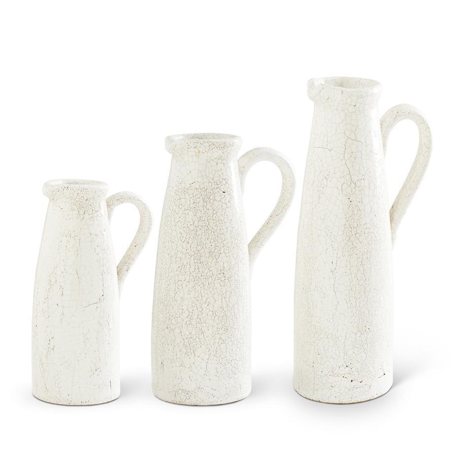 Set of three white ceramic crackled pitchers in varying heights with handles.