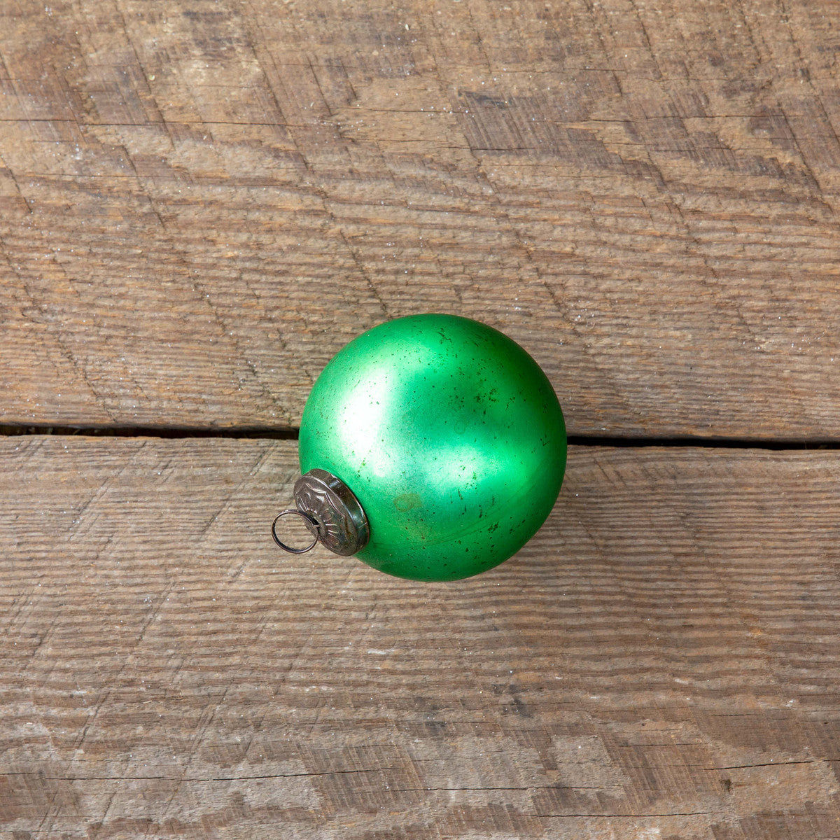 Antique matte emerald green glass ball ornament on a rustic wood background.