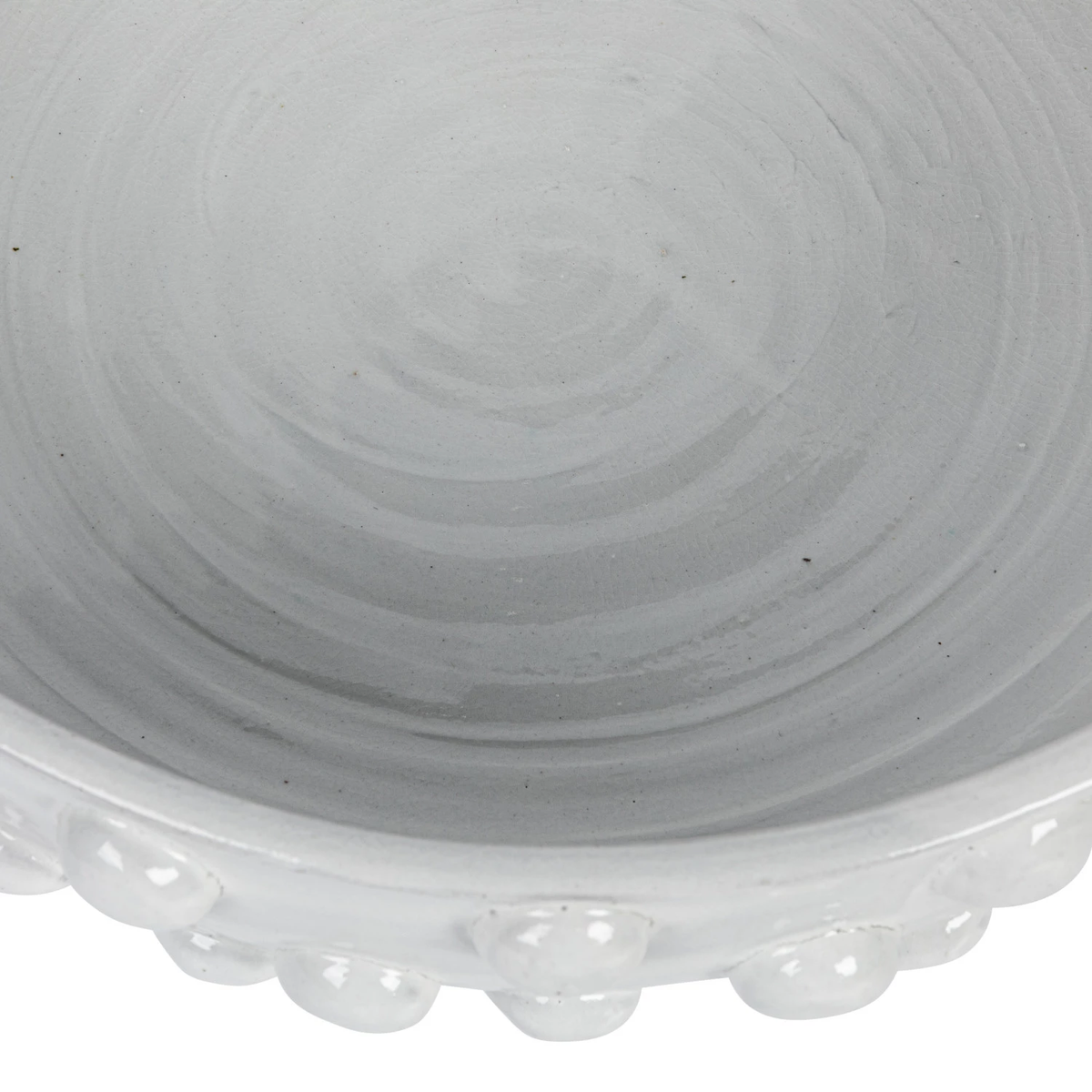 Close-up of a white terracotta bowl with a crackle glaze and raised dots along the exterior rim.