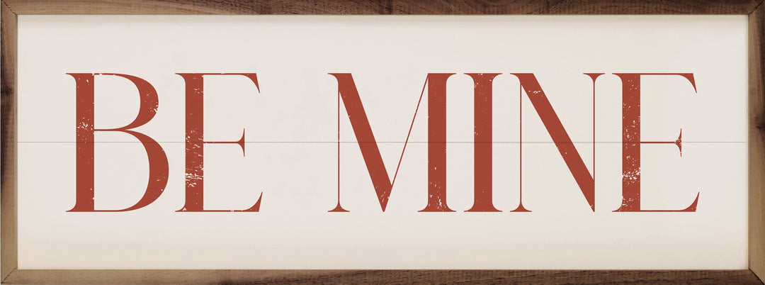 Red "BE MINE" text on a white wood plank background with a natural walnut frame.