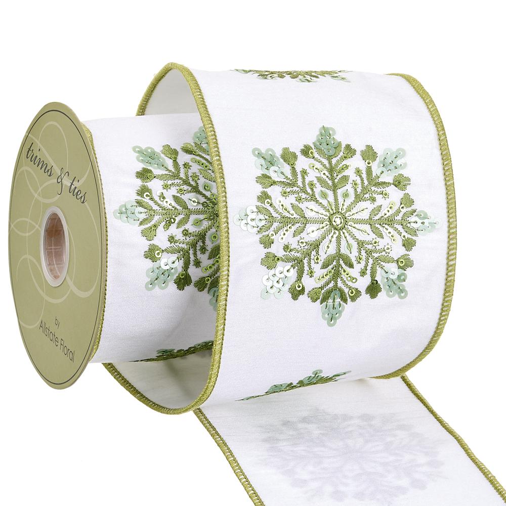 4-inch wide white ribbon with green embroidered snowflakes and sequins on a spool.