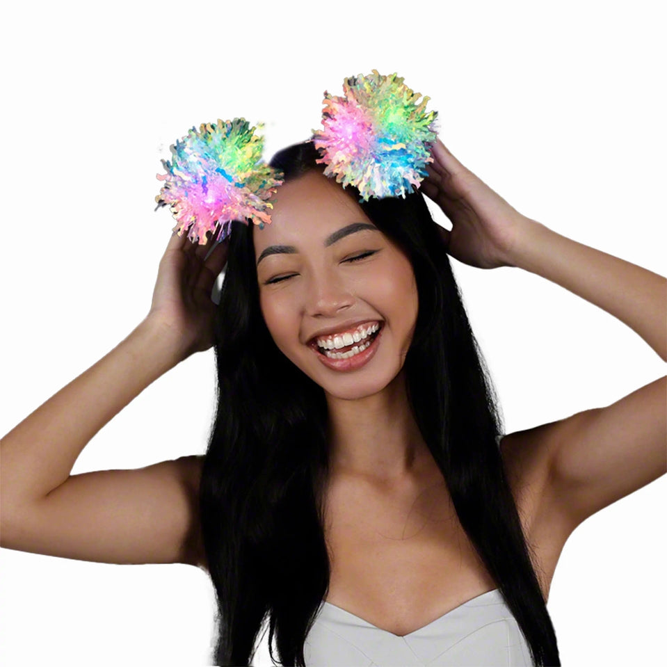 Woman wearing a light-up headband with two multicolored crinkle tinsel fluffy pom poms.