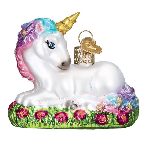 Glass baby unicorn ornament lying in a field of pink wildflowers with a glittery mane and gold horn.