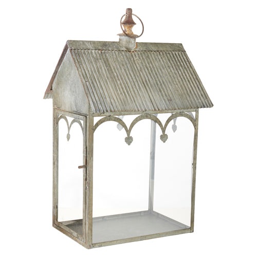 24-inch antiqued metal lantern with a corrugated gabled roof and decorative arched glass panels.