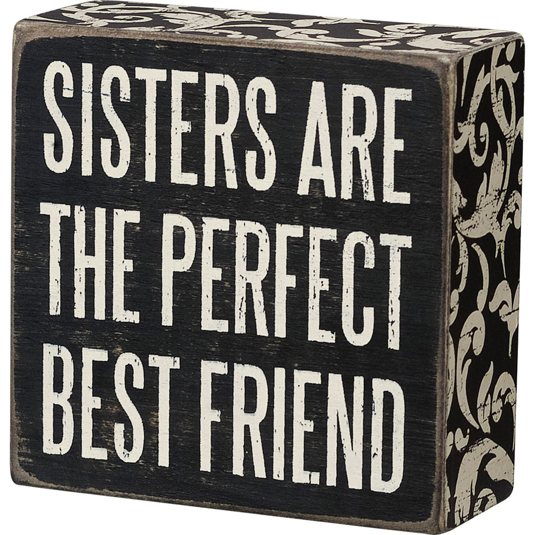 Black wooden box sign with white text reading "SISTERS ARE THE PERFECT BEST FRIEND".