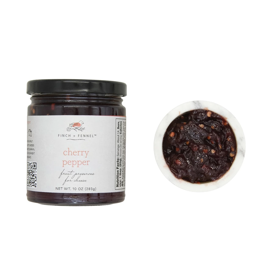 Open jar of cherry pepper fruit preserves with visible red cherries and green peppers.