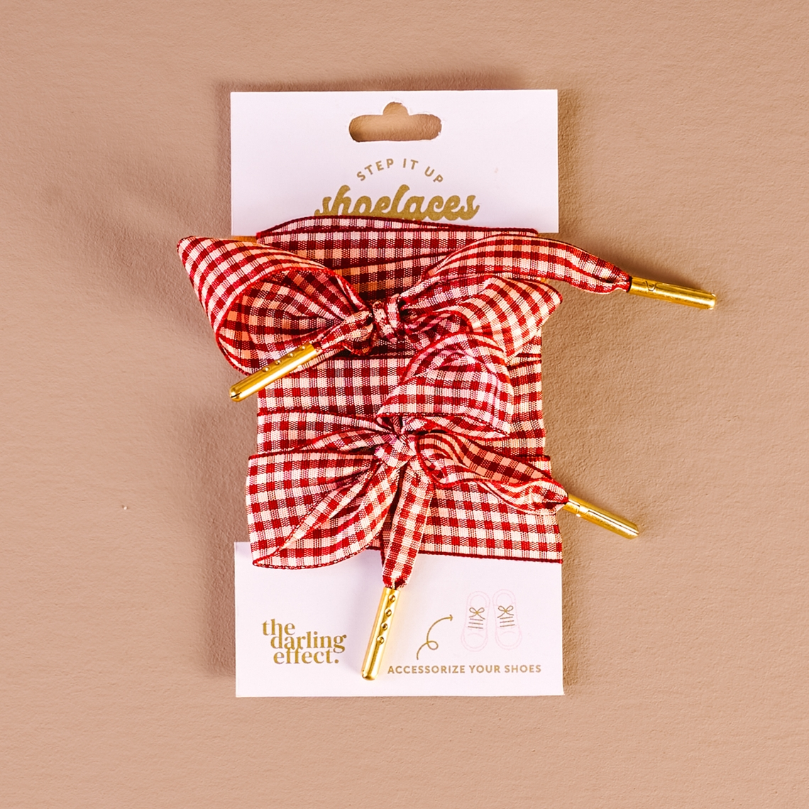 Red and white gingham patterned shoelaces with gold metal tips on a white display card.