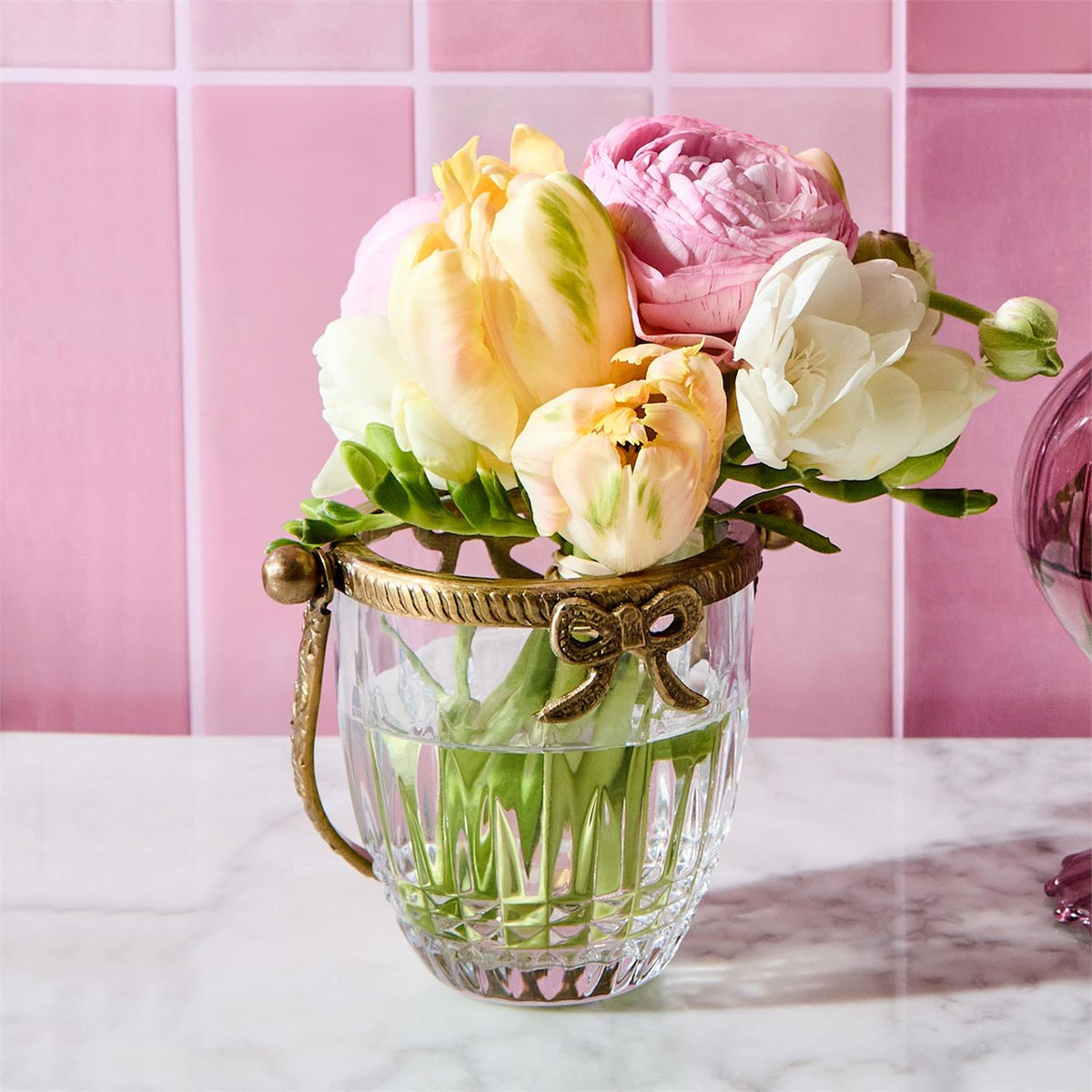Antique gold finish glass basket with a bow accent holding a bouquet of pink and yellow flowers.