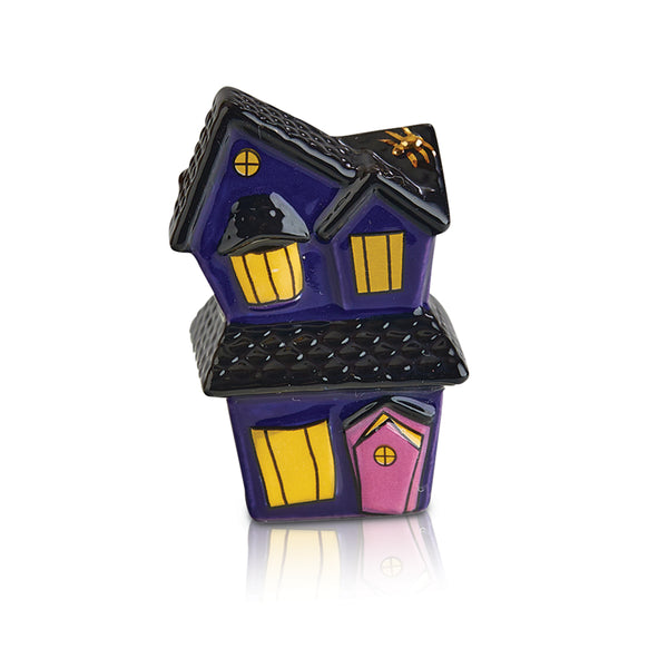 Purple ceramic haunted house figurine with yellow windows, black roof, and a pink door.