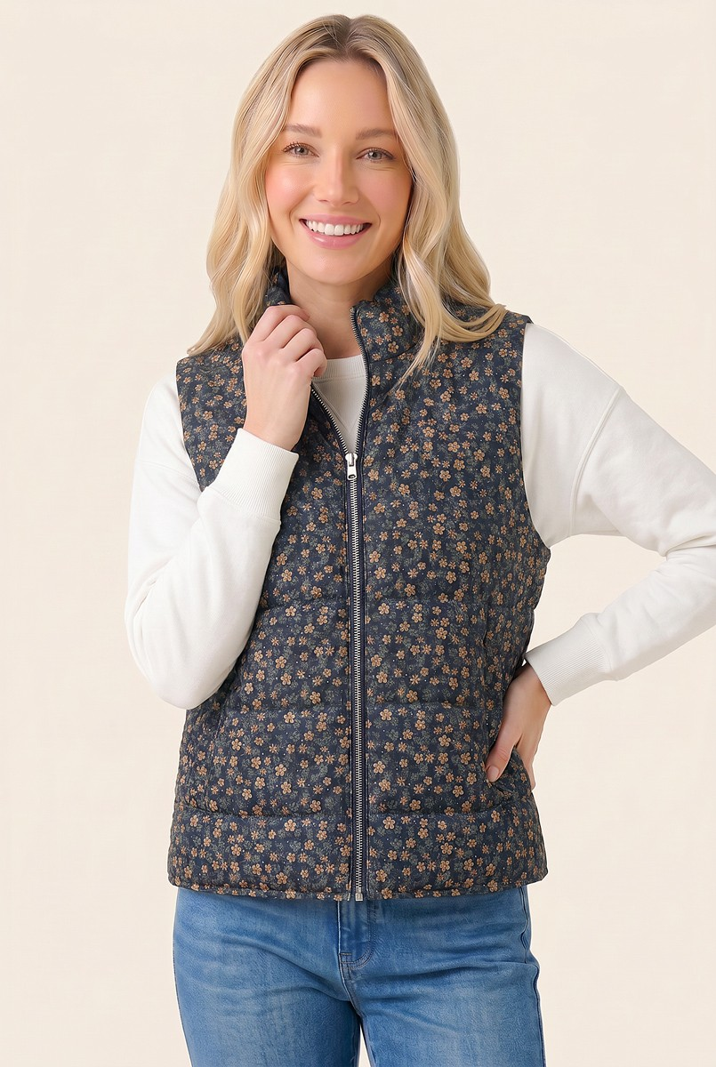 Woman wearing a Clara Corduroy Floral Printed Puffer Vest in navy with tan flowers over a white top.