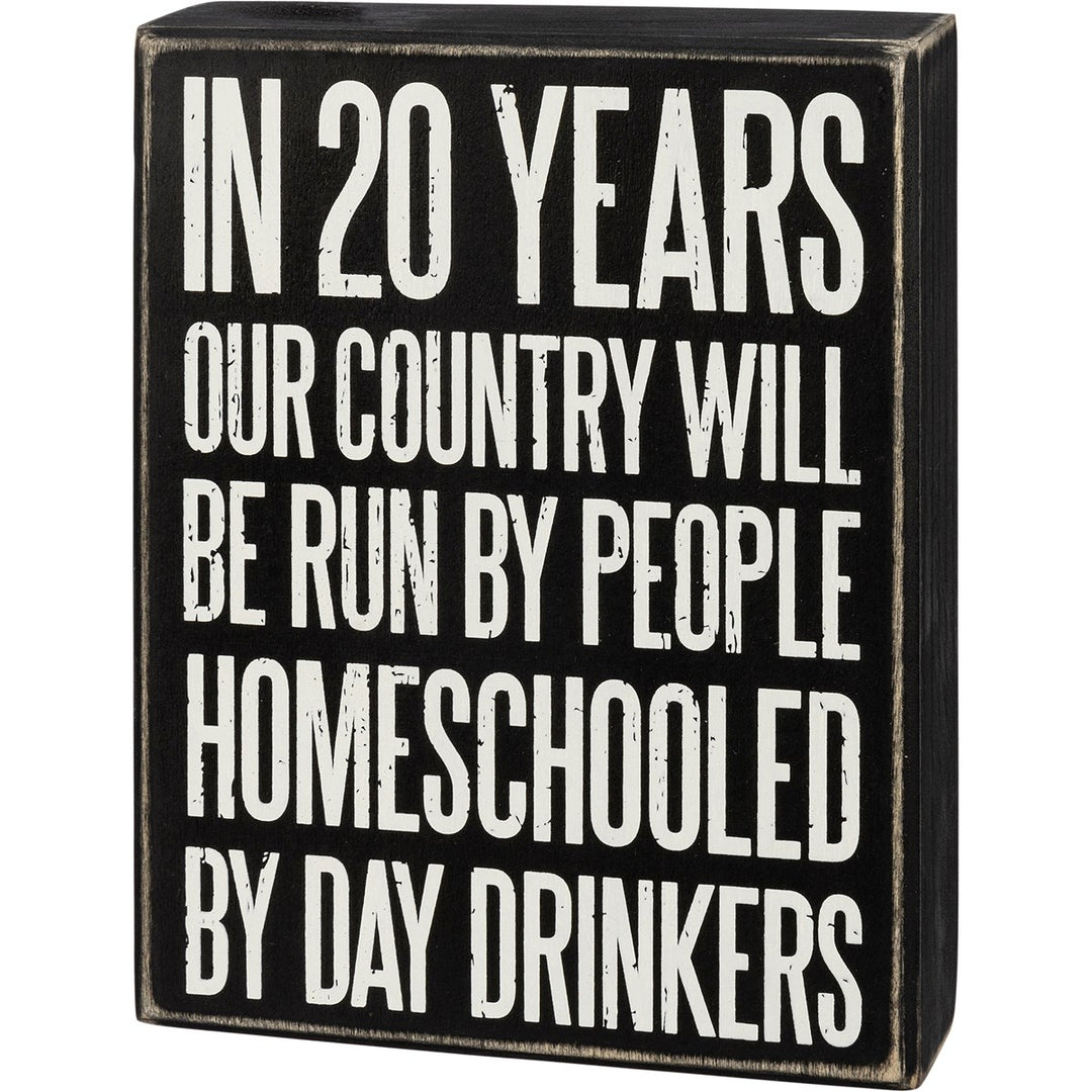 A black wooden box sign with distressed edges featuring white text about homeschooling.