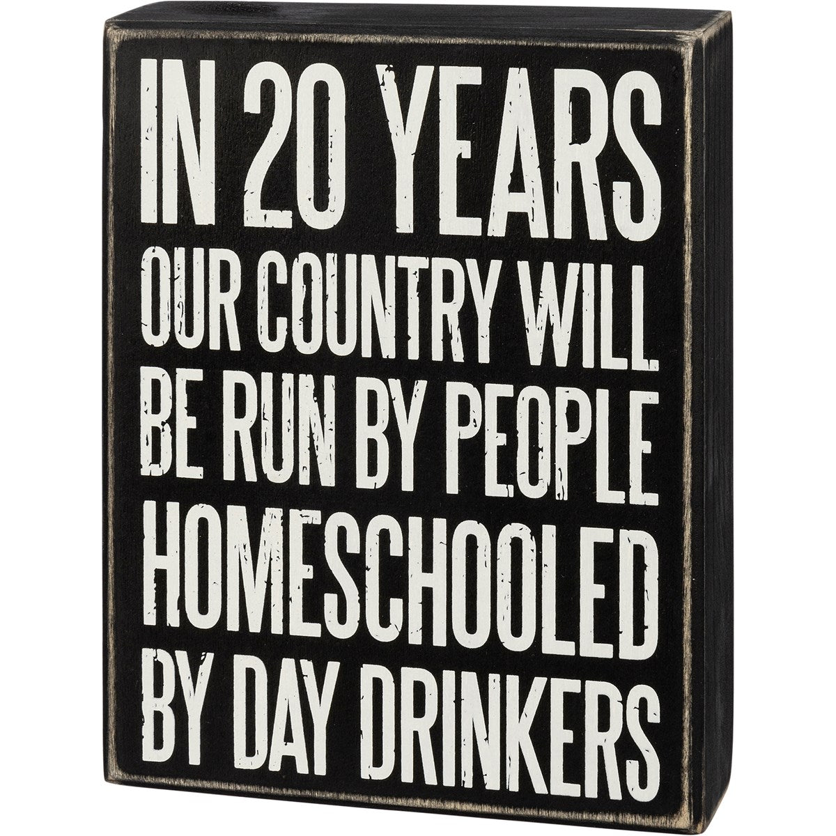 A black wooden box sign with distressed edges featuring white text about homeschooling.