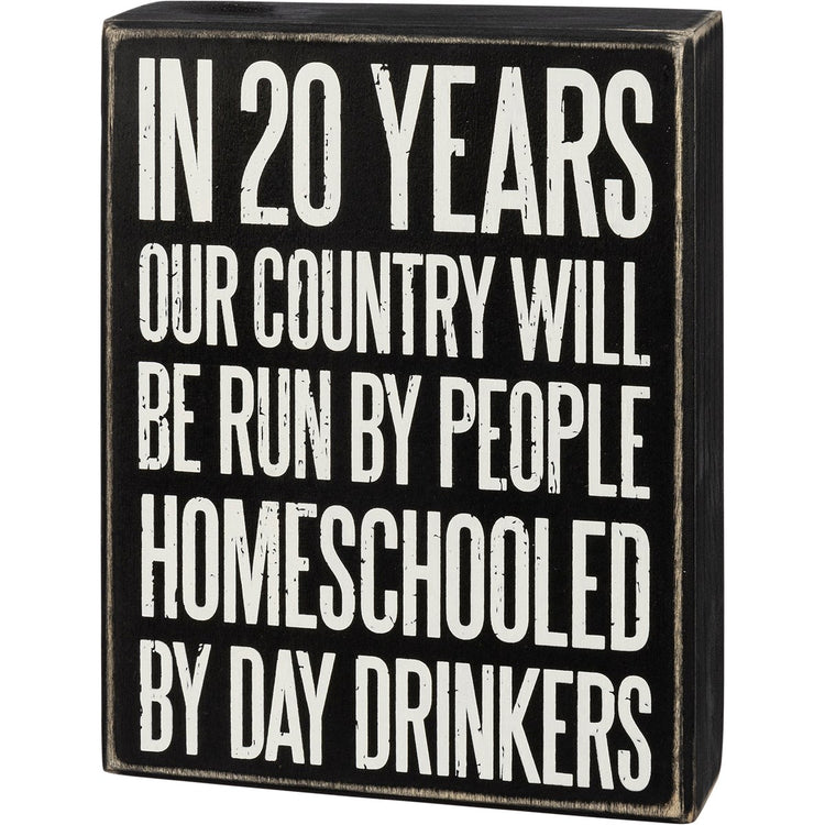 A black wooden box sign with distressed edges featuring white text about homeschooling.