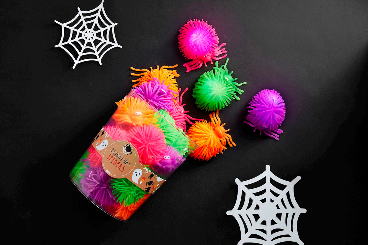 Black rubber spider decoration with glowing eyes on a white background.