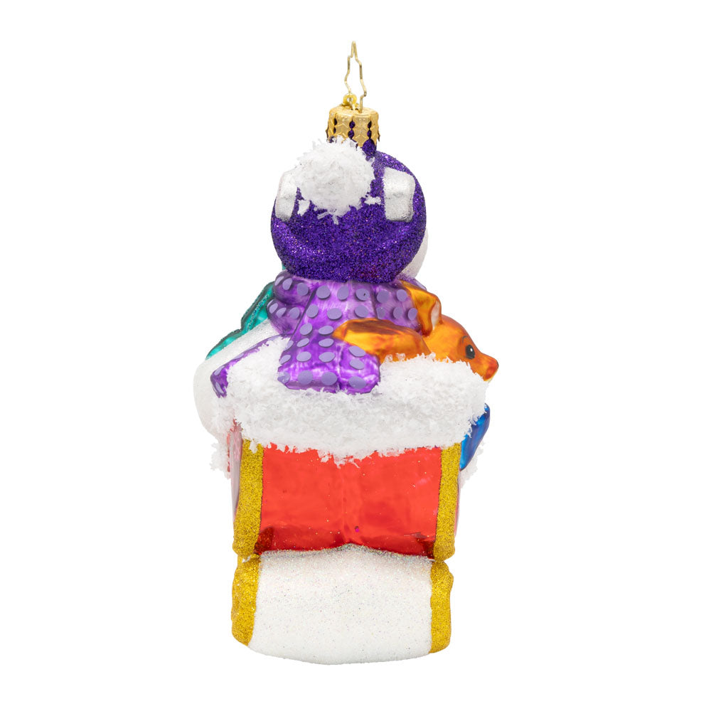 Back view of a glass sleigh ornament with a purple-hatted snowman and a small orange animal.