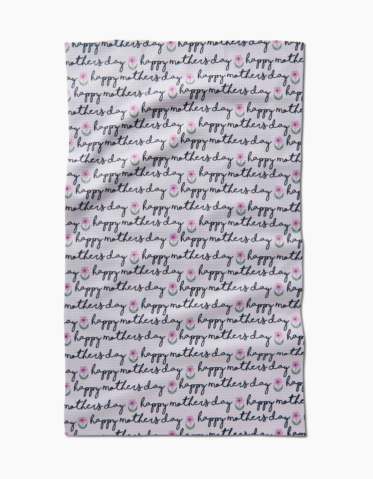 Waffle weave Mother's Day tea towel with a repeating 'happy mothers day' script and flower pattern.
